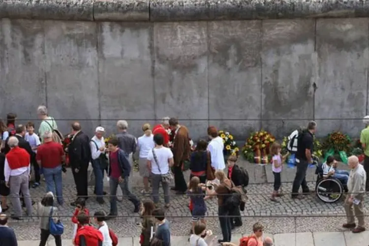
	Alem&atilde;es junto ao muro de Berlim: p&uacute;blico poder&aacute; viajar no tempo at&eacute; um dia fict&iacute;cio dos anos 80 e acompanhar o dia a dia das pessoas
 (Getty Images)