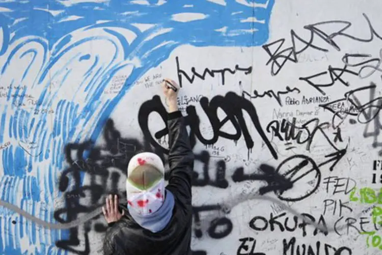 
	Turista escreve uma mensagem no Muro de Berlim: &quot;H&aacute; uma identidade brasileira no grafite&quot;, declarou o artista Speto, 41 anos, um dos pioneiros da arte urbana no Brasil.
 (John Macdougall/AFP)