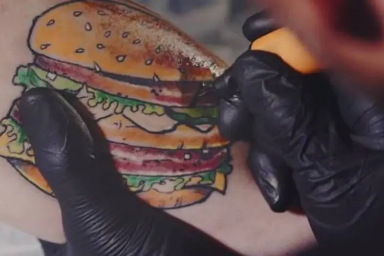 
	Tatuagem do Big Mac, o sandu&iacute;che mais famoso do McDonald&#39;s, sendo refeita
 (Reprodução/YouTube)