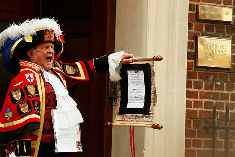Homem vestido com roupas tradicionais anuncia o nascimento de uma menina aos fãs da família real e à mídia na entrada do Hospital St Mary, em Londres (REUTERS/Cathal McNaughton)