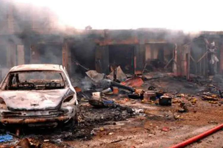 
	Carro destru&iacute;do diante de lojas que foram alvo de atentado em mercado
 (AFP)