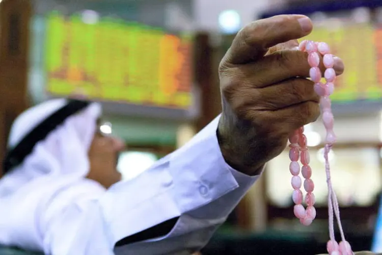 Homem rezando com um terço árabe na Bolsa de Valores de Dubai, nos Emirados Árabes Unidos (Duncan Chard/Bloomberg)