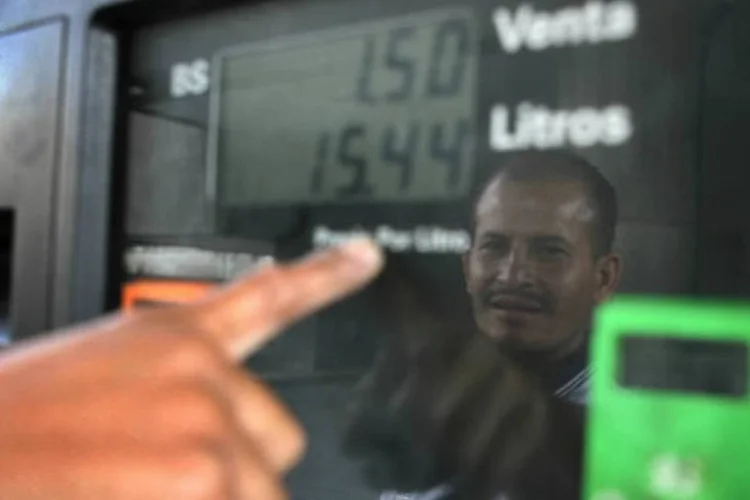 Frentista aponta para visor de bomba de gasolina em Caracas, Venezuela (Susana Gonzalez/Bloomberg News)