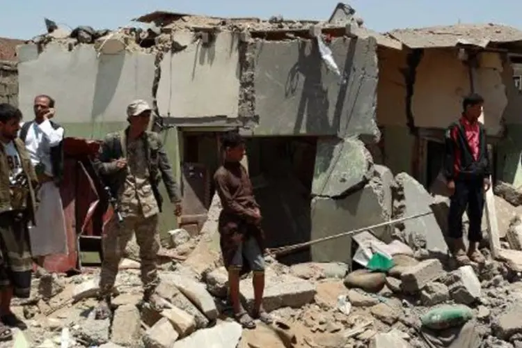 Iemenitas em meio a escombros de casas perto do aeroporto de Sana, após ataque aéreo da coalizão (Mohammed Huwais/AFP)