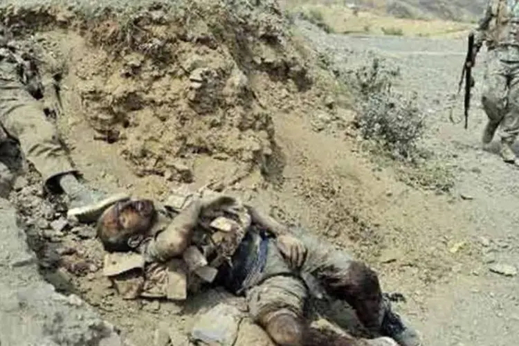 Militares afegãos observam corpos de insurgentes talibãs após combates em Torkham em 2 de setembro (AFP)