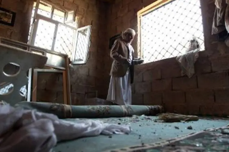 Homem limpa os destroços em sua casa, após bombardeios aéreos realizados próximo ao aeroporto de Sana (Mohammed Huwais/AFP)