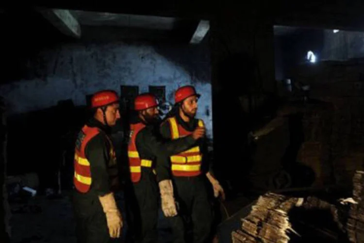
	Bombeiros fazem buscas em f&aacute;brica incendiada: a suspeita &eacute; de que faltava seguran&ccedil;a nas instala&ccedil;&otilde;es
 (Arif Ali/AFP)