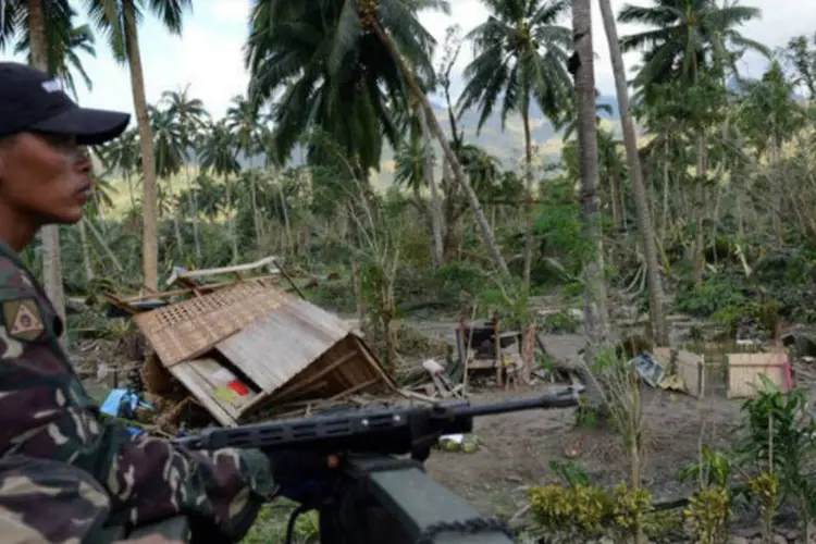 Soldado filipino observa área devastada pelo tufão Bopha na cidade de New Bataan, nas Filipinas (AFP/ Ted Aljibe)