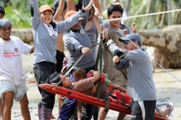 
	Equipes resgatam uma mulher e seu filho em Nova Bataan, durante a passagem do tuf&atilde;o: as equipes de socorro recuperaram pelo menos 477 corpos nesta quinta-feira
 (Ted Aljibe/AFP)