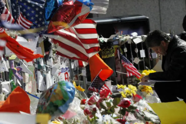 Homem ajoelha-se para depositar mensagem em memorial, depois de fazer um minuto de silêncio pelas vítimas das explosões na Maratona de Boston (REUTERS/Jessica Rinaldi)