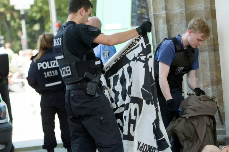 
	Policial v&ecirc; bandeira de extremistas ap&oacute;s protesto em Berlim: eles pediam o fim da &quot;islamiza&ccedil;&atilde;o&quot; da Alemanha
 (Stefanie Loos/Reuters)