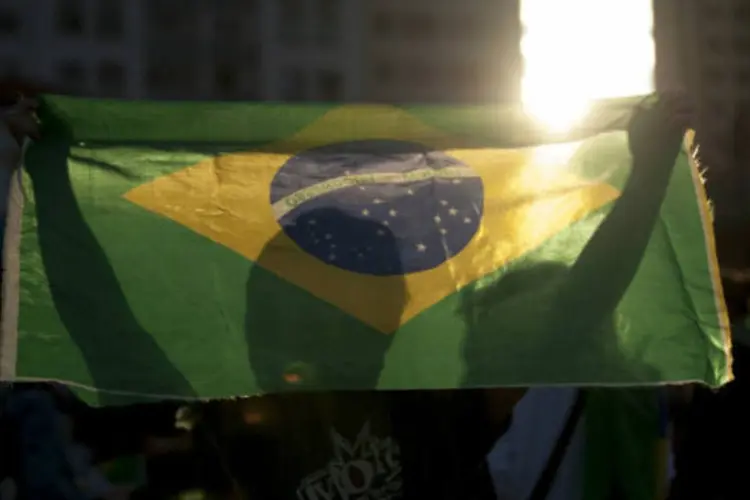
	Manifestante carrega bandeira do Brasil durante protesto contra o aumento das tarifas do transporte p&uacute;blico em S&atilde;o Paulo
 (Marcelo Camargo/ABr)