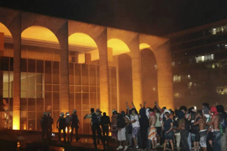
	Na tentativa de invadir o Pal&aacute;cio do Itamaraty, manifestantes chegaram a colocar fogo em uma das entradas da sede do Minist&eacute;rio das Rela&ccedil;&otilde;es Exteriores, em Bras&iacute;lia, nesta quinta-feira: ideia &eacute; impedir que o pr&eacute;dio seja alvo de ataques, como os ocorridos h&aacute; menos de uma semana
 (REUTERS/Gustavo Froner)
