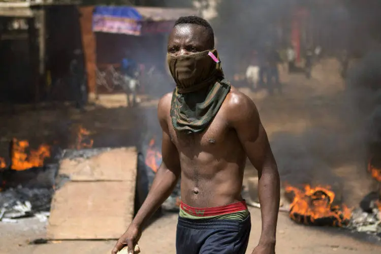 
	Manifestante em meio fuma&ccedil;a de inc&ecirc;ndio em rua de Ouagadougou, capital de Burkina Faso
 (Joe Penney/Reuters)