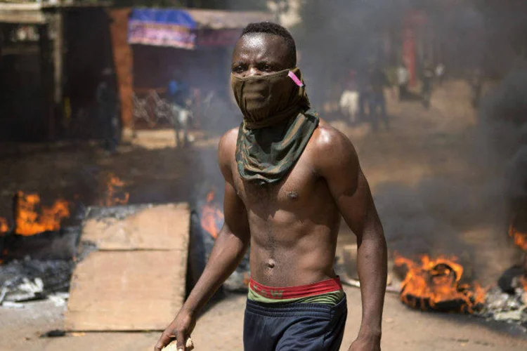 
	Manifestante em meio a fuma&ccedil;a de inc&ecirc;ndio em rua de Ouagadougou, capital de Burkina Faso
 (Joe Penney/Reuters)