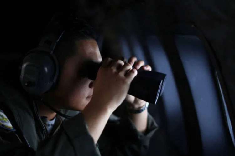 Um membro da Força Aérea Real da Malásia usa um binóculo durante uma operação de busca e resgate para encontrar o voo MH370 da Malaysia Airlines (Samsul Said/Reuters)