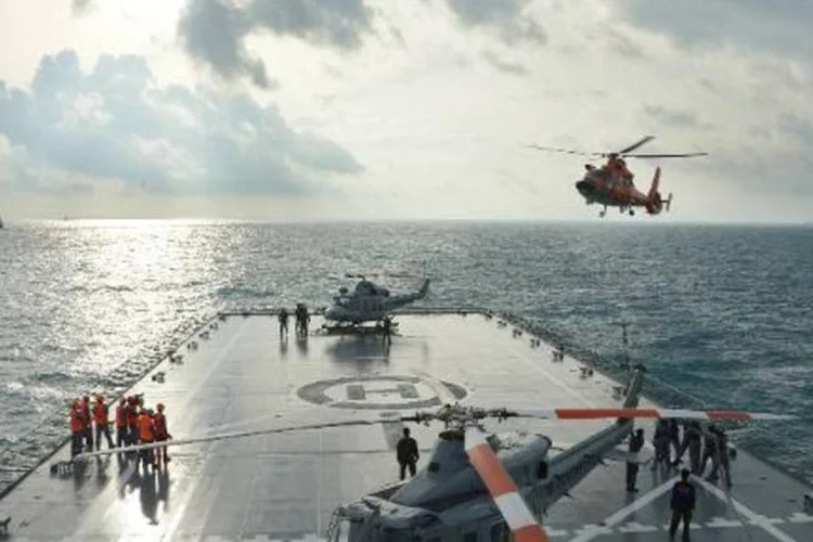 Um helicóptero de resgate se prepara para pousar em uma embarcação indonésia durante as operações de busca dos destroços do avião da AirAsia (Adek Berry/AFP)