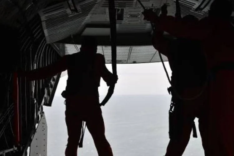 Tripulantes do avião CN295 da força aérea indonésia observam o mar durante buscas por avião da AirAsia (Bay Ismoyo/AFP)