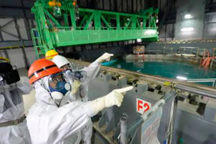 Governador de Fukushima, Yuhei Sato (capacete laranja) inspeciona o reator 4 da central nuclear em 15 de outubro
 (JAPAN POOL/AFP)