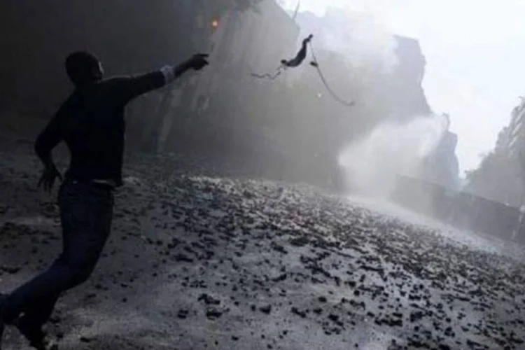 Manifestante egípcio joga objeto contra forças de segurança durante confrontos na praça Tahrir, no Cairo (Mohammed Hossam/ AFP)