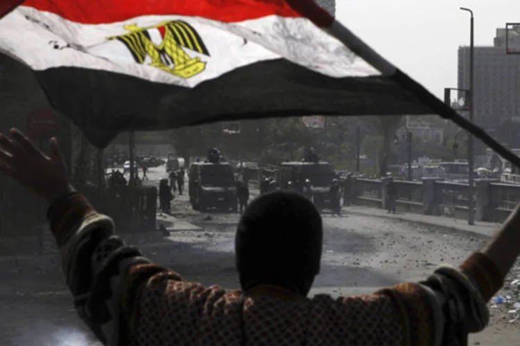 Manifestante contrário ao presidente Mohamed Mursi segura bandeira nacional durante confronto com a polícia no Cairo (Amr Abdallah Dalsh/Reuters)