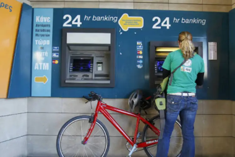 Mulher saca dinheiro em caixa eletrônico do lado de fora de agência do Banco do Chipre (REUTERS/Bogdan Cristel)
