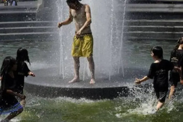 Crianças usam fonte em parque de Nova York para se refrescar: as altas temperaturas provocaram problemas em estradas, aeroportos e edifícios, assim como incêndios (Timothy A. Clary/AFP)