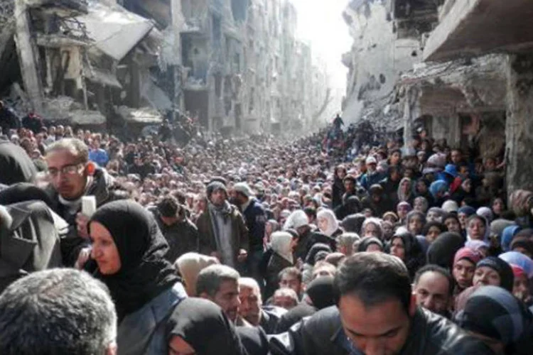 Imagem divulgada pela Agência de Ajuda e Trabalho da ONU (UNRWA) de 26 de fevereiro mostra moradores de Yarmuk, em distribuição de comida (Divulgação via AFP)