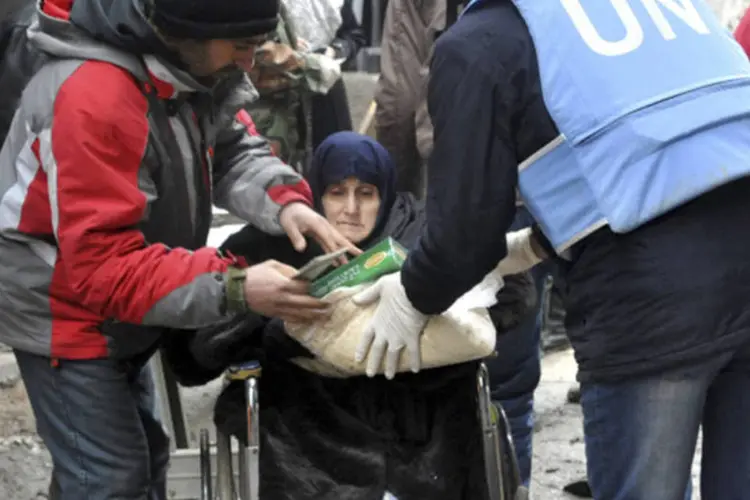 
	Moradores recebem ajuda humanit&aacute;ria da ONU no campo de refugiados de al-Yarmouk, ao sul de Damasco
 (SANA/Divulgação via Reuters)