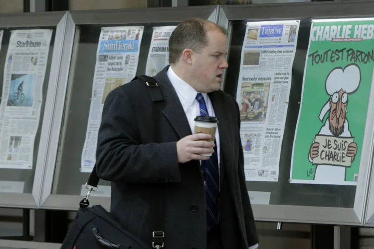 Homem observa capa da última edição do jornal Charlie Hebdo ao lado de jornais americanos (Gary Cameron/Reuters)