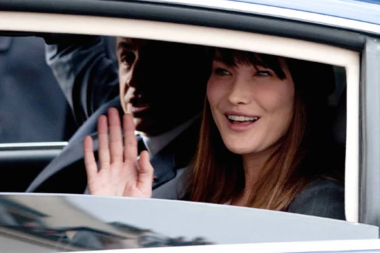 Carla Bruni acena de dentro de carro: o fato das mulheres não receberem o mesmo que os homens era um dos motivos para o feminismo mais citados pelos usuários do Twitter (Trago/ Getty Images)