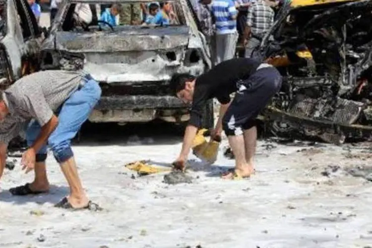 
	Moradores recolhem objetos diante de carros queimados numa explos&atilde;o em Bagd&aacute;:&nbsp;carros-bomba explodiram perto de um quartel-general da pol&iacute;cia em Baladiyat

	
	
 (AFP)