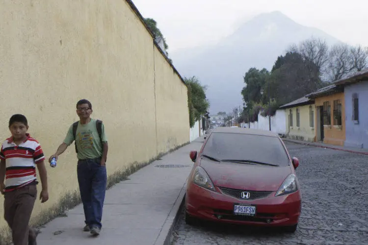Pessoas caminham próximas a carro coberto de cinzas de vulcão na Guatemala (Josue Decavele/Reuters)