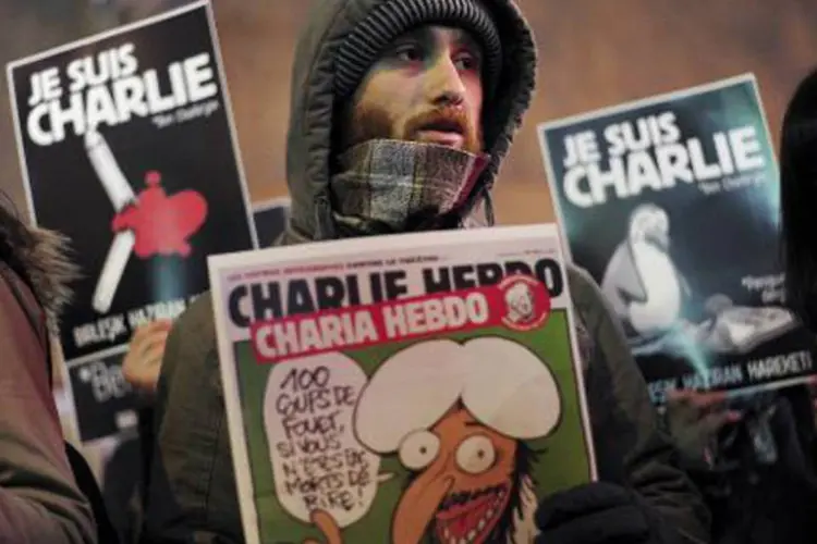 Pessoas seguram cartazes com imagens de capa do jornal Charlie Hebdo (Ozan Kose/AFP)