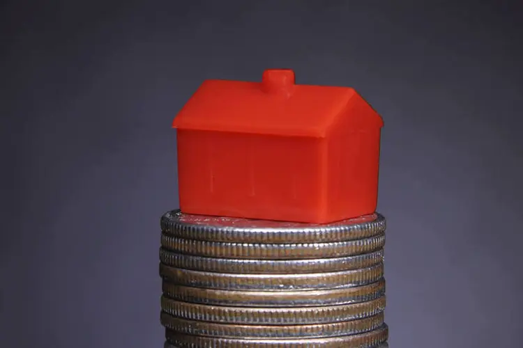 
	Casa em miniatura sobre moedas: Para um im&oacute;vel de R$ 300 mil, o valor do imposto passou de R$ 4.901,14 para R$ 7.168,57
 (ThinkStock/pkstock)