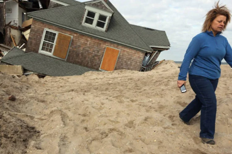 
	Moradora caminha depois de voltar de sua casa destru&iacute;da em Bay Head, Nova Jersey: pacote de ajuda a propriet&aacute;rios conta com 60 bilh&otilde;es de d&oacute;lares
 (Getty Images/ Mario Tama)