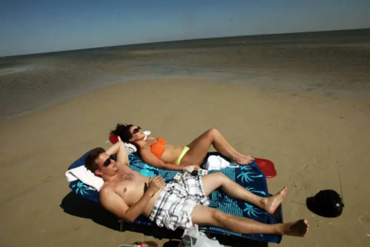 
	Casal na praia: economia de 7 mil reais por m&ecirc;s para ganhar 10 mil reais
 (Getty Images / Allison Shelley)