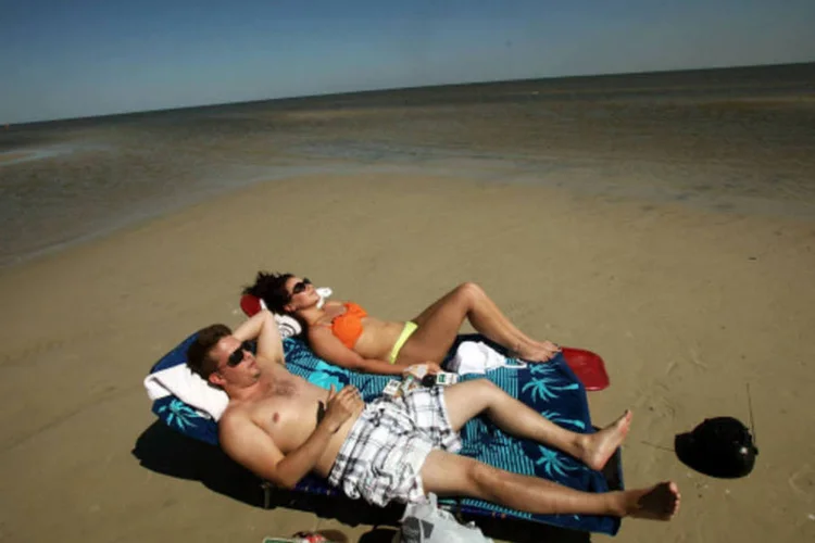 
	Casal na praia: economia de 7 mil reais por m&ecirc;s para ganhar 10 mil reais
 (Getty Images / Allison Shelley)