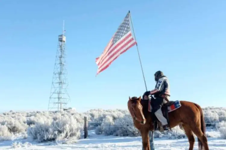 Homem montado em cavalo segura a bandeira dos Estados Unidos (Rob Kerr/AFP)