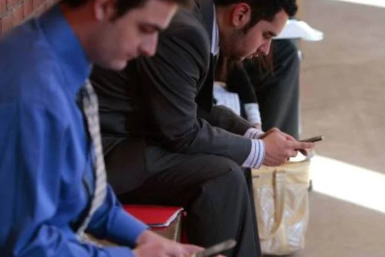 Pessoas no celular: há mais interação entre homem e smartphone do que networking entre colegas.