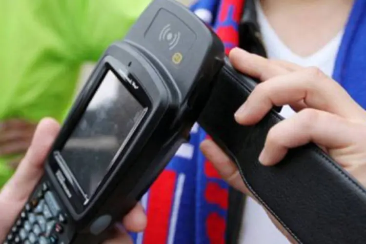 Torcedor paga ingresso para jogo de futebol com o seu celular em um terminal com leitor NFC, a opção preferida por operadoras e bancos (Kenzo Tribouillard/AFP)