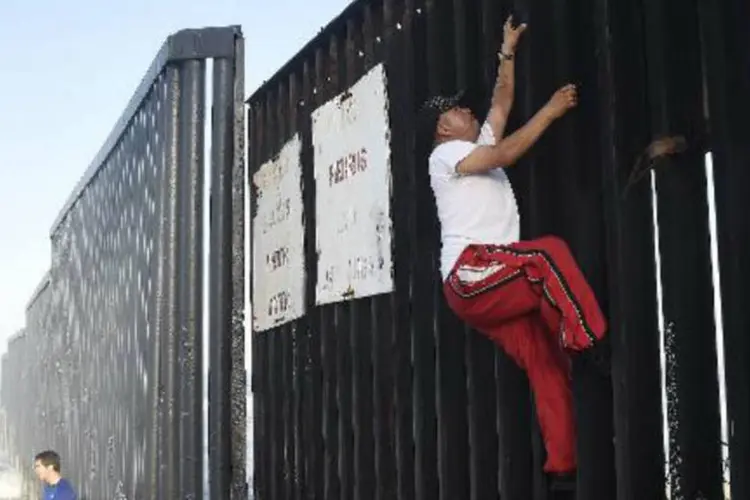 Homem tenta ultrapassar a cerca na fronteira com os Estados Unidos, na cidade mexicana de Tijuana (Ronaldo Schemidt/AFP)