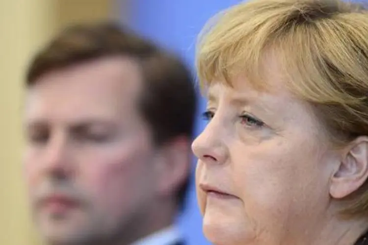 A chanceler alemã, Angela Merkel, ao lado do seu porta-voz, Steffen Seibert (John MacDougall/AFP)