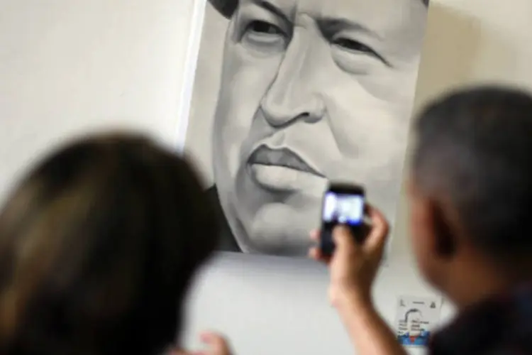 Visitantes tiram fotos de uma pintura retratando o presidente venezuelano, Hugo Chávez, em uma exposição em Caracas  (REUTERS / Jorge Silva)
