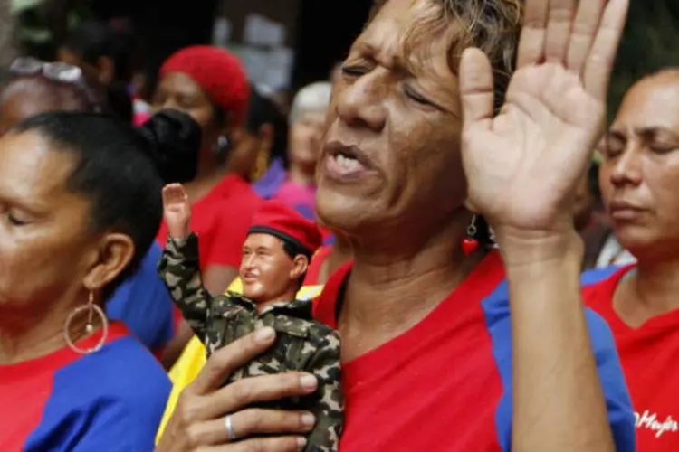 
	Mulher com boneco do presidente em meio &agrave; multid&atilde;o que reza por Ch&aacute;vez em Caracas: oposi&ccedil;&atilde;o venezuelana declarou que informa&ccedil;&otilde;es oficiais sobre sua sa&uacute;de n&atilde;o s&atilde;o claras
 (REUTERS / Carlos Garcia Rawlins)