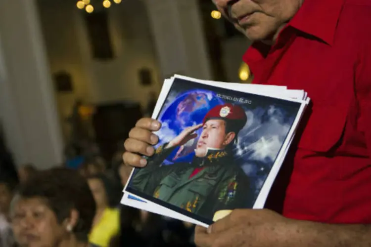 
	Apoiador de Hugo Ch&aacute;vez segura uma foto do presidente venezuelano durante missa por sua sa&uacute;de, em Caracas
 (REUTERS / Carlos Garcia Rawlins)