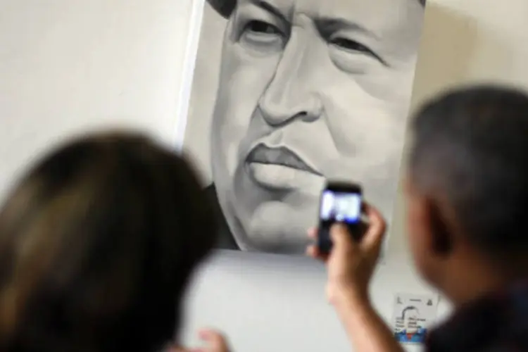 
	Visitantes tiram fotos de uma pintura de Hugo Ch&aacute;vez: museu&nbsp;lembra&nbsp;&quot;a hist&oacute;ria de um homem rebelde, um guerreiro, um lutador&quot;, disse Nicol&aacute;s Maduro
 (REUTERS / Jorge Silva)