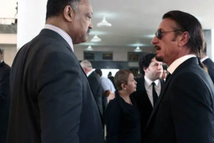O reverendo americano Jesse Jackson (e) e o ator Sean Penn conversam durante o funeral de Hugo Chávez (AFP / Ho)