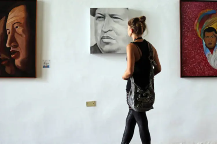 Mulher olha pintura do presidente Hugo Chávez em mostra que o homenageia em um prédio governamental de Caracas (Jorge Silva/Reuters)