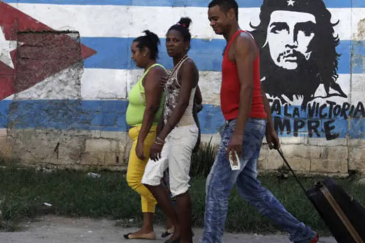 Pessoas caminham em frente a um mural com a imagem do líder revolucionário Che Guevara em Havana, Cuba (Enrique De La Osa/Reuters)